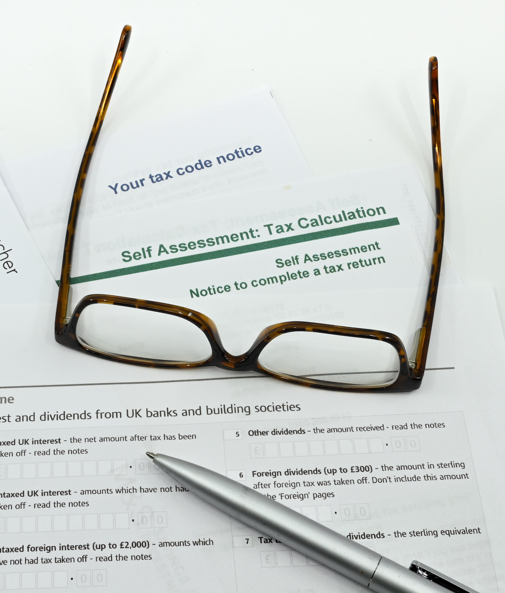 Tax code notice and self-assessment documents with glasses and pen